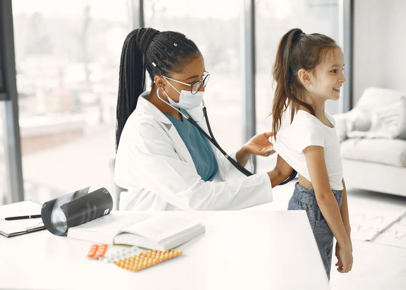 A clinician listens to a young girl's breathing with a stethoscope